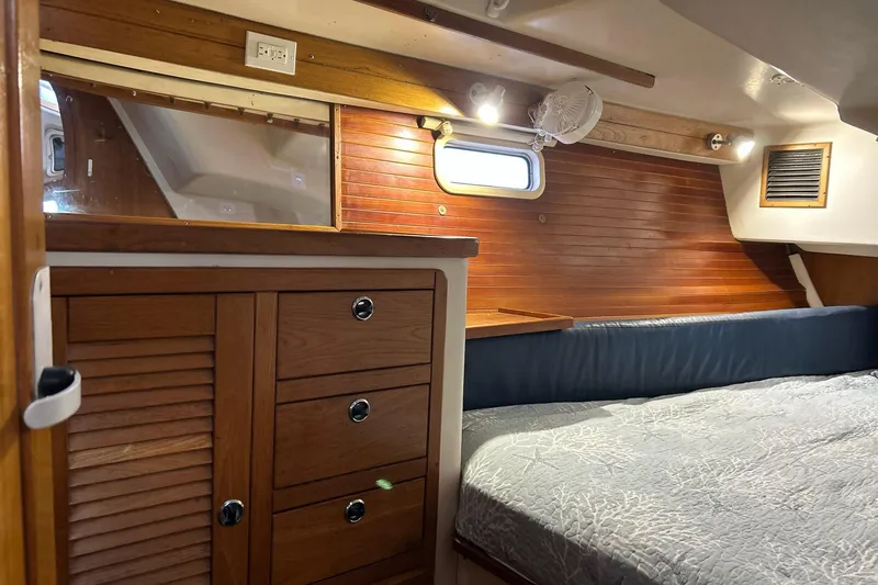 Slide: The Image of Interior of a 1999 Catalina 42 MkII sailboat cabin with wooden cabinetry and cozy bedding. - 12