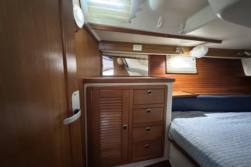 Slide: The Image of Interior of a 1999 Catalina 42 MkII sailboat cabin with wooden cabinetry and bed. - 42