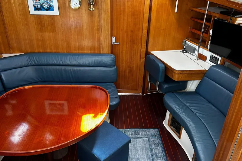 Slide: The Image of Interior of a 1999 Catalina 42 MkII yacht with blue seating and wooden table. - 5