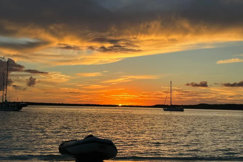 Slide: The Image of Sunset over calm waters with sailboats, featuring a 1999 Catalina 42 MkII. - 61
