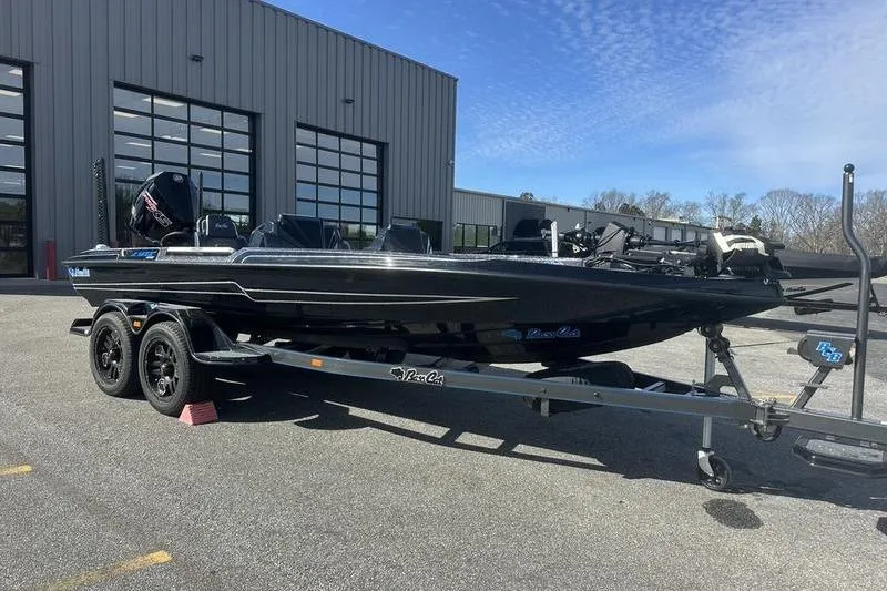 Slide: The Image of 2026 Bass Cat Lynx STS boat on trailer, parked outside a modern building. - 3
