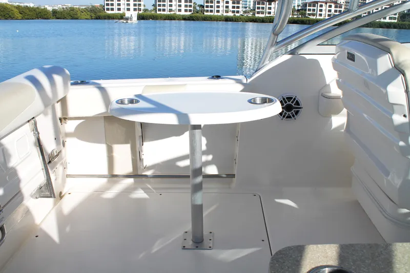 Slide: The Image of 2016 Robalo R247 Dual Console boat interior with table, cup holders, and scenic water view. - 19