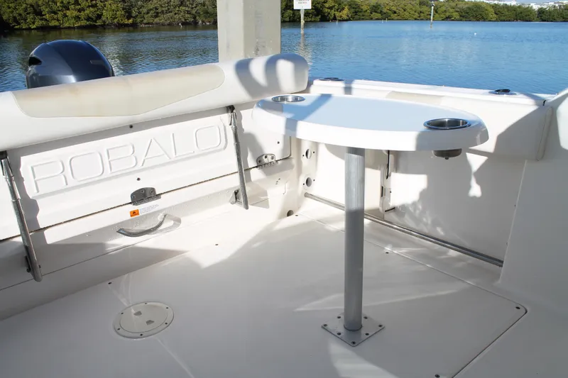 Slide: The Image of 2016 Robalo R247 Dual Console boat interior with table and seating, near water. - 20