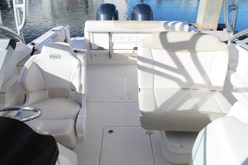 Slide: The Image of 2016 Robalo R247 Dual Console boat interior with white seating and water backdrop. - 26