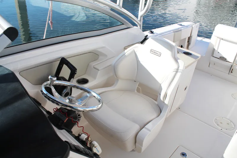Slide: The Image of 2016 Robalo R247 Dual Console boat interior with steering wheel and white seating. - 28