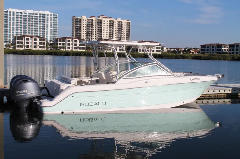 Slide: The Image of 2016 Robalo R247 Dual Console boat docked on calm water with cityscape background. - 5
