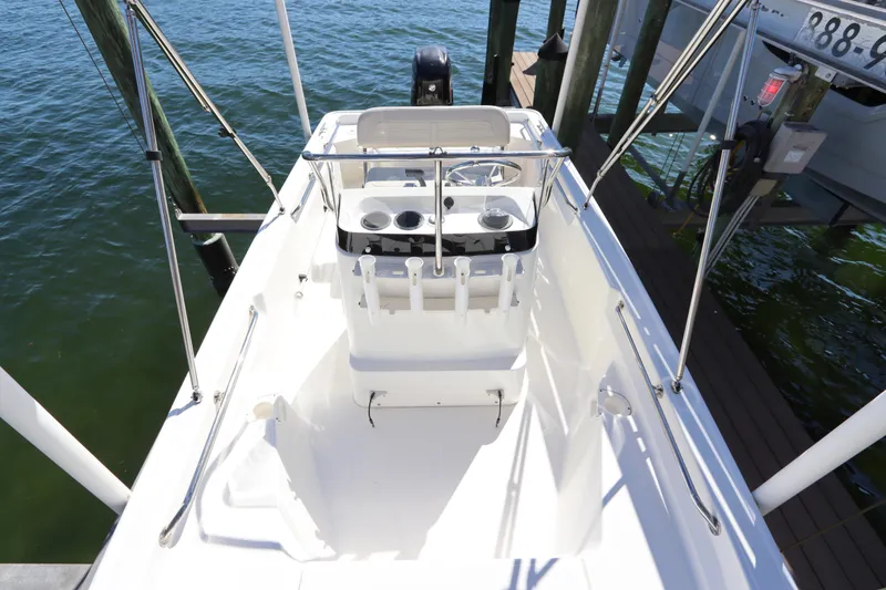 Slide: The Image of 2020 Boston Whaler 150 Montauk boat interior with console and seating, docked on water. - 13