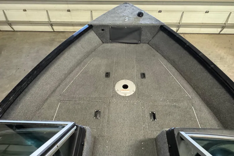 Slide: The Image of 2017 Lund 1750 Rebel XS Sport boat interior with carpeted deck and storage compartments. - 12