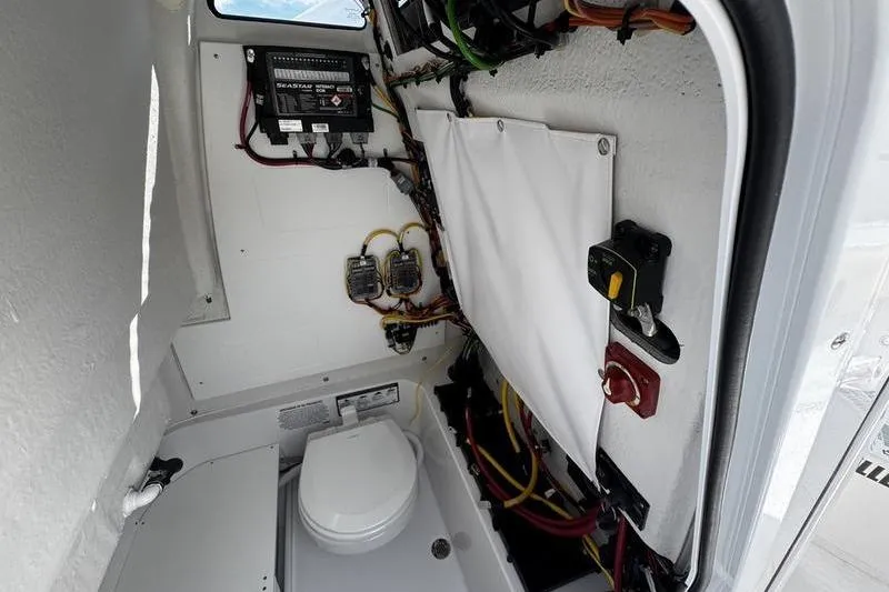 Slide: The Image of Interior of 2026 Sportsman Open 232 Center Console boat, featuring wiring and a compact toilet. - 20