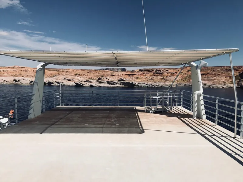 Slide: The Image of Houseboat deck with sunshade, calm water, and rocky shoreline in the background. - 44