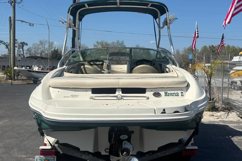 Slide: The Image of 2005 Sea Ray 220 Select boat, rear view, parked outdoors with flags in the background. - 2