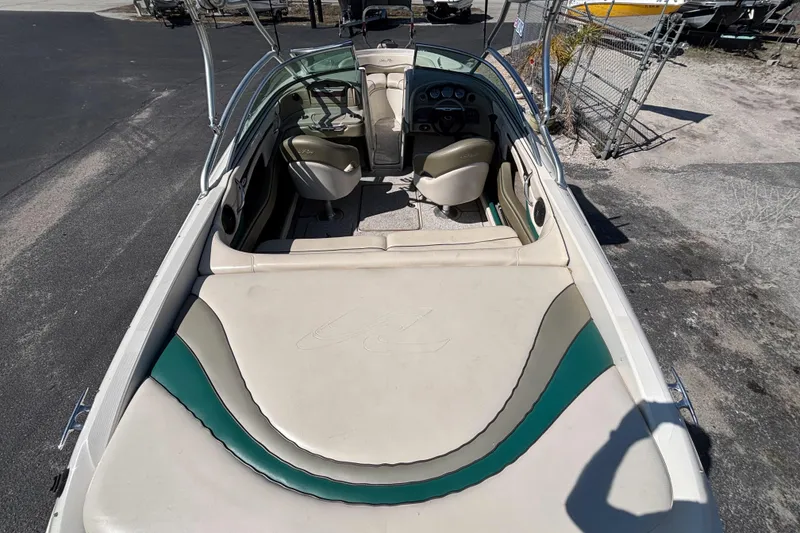 Slide: The Image of 2005 Sea Ray 220 Select boat interior with beige and teal seating, parked on pavement. - 23