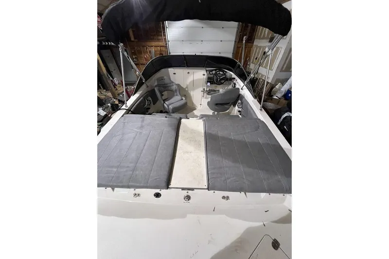 Slide: The Image of 2020 Stingray 208 CR boat interior with seating and canopy in a garage setting. - 13