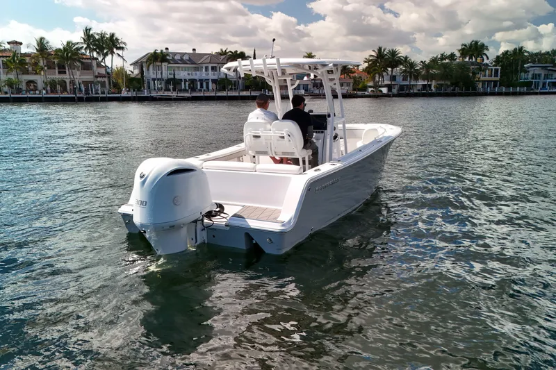 Slide: The Image of 2018 Sportsman Heritage 241 Center Console boat cruising on a sunny waterfront. - 2