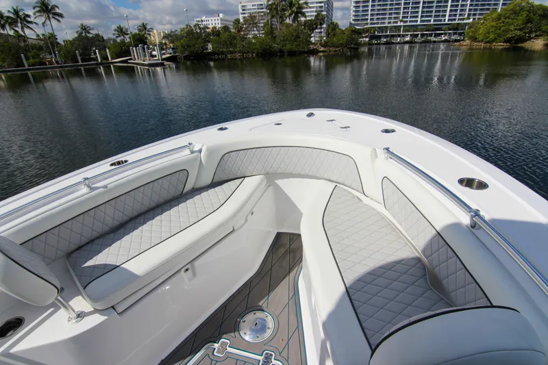 Slide: The Image of 2018 Sportsman Heritage 241 Center Console boat with cushioned seating, docked near lush greenery. - 21