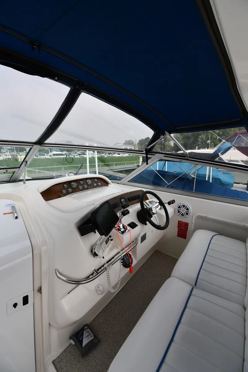 Slide: The Image of 1995 Sea Ray 330 Sundancer cockpit with steering wheel, controls, and seating under blue canopy. - 11
