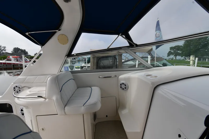 Slide: The Image of 1995 Sea Ray 330 Sundancer interior with white seating and blue accents, docked at marina. - 17