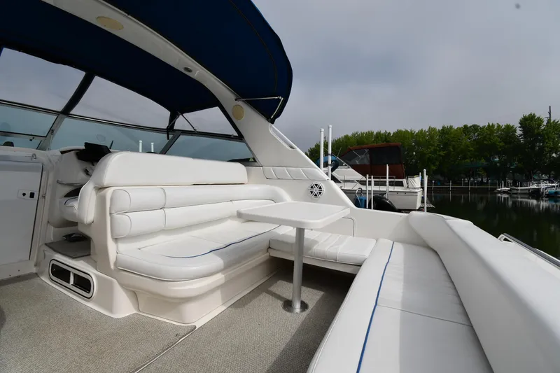 Slide: The Image of 1995 Sea Ray 330 Sundancer interior with white seating and table, docked by a marina. - 19