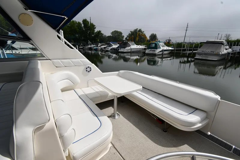 Slide: The Image of 1995 Sea Ray 330 Sundancer boat interior with white seating and table, docked at marina. - 24