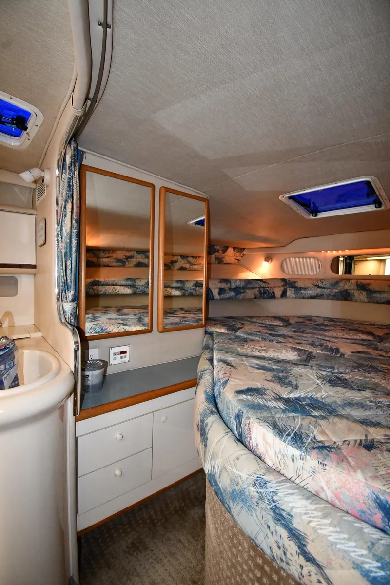 Slide: The Image of 1995 Sea Ray 330 Sundancer cabin interior with bed, mirrors, and storage. - 33