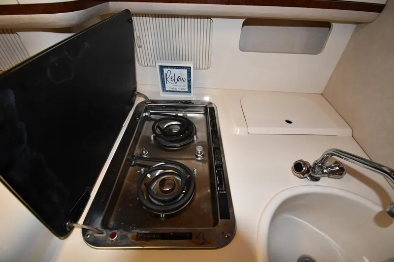 Slide: The Image of 1995 Sea Ray 330 Sundancer kitchen with stove, sink, and "Relax" sign. - 45