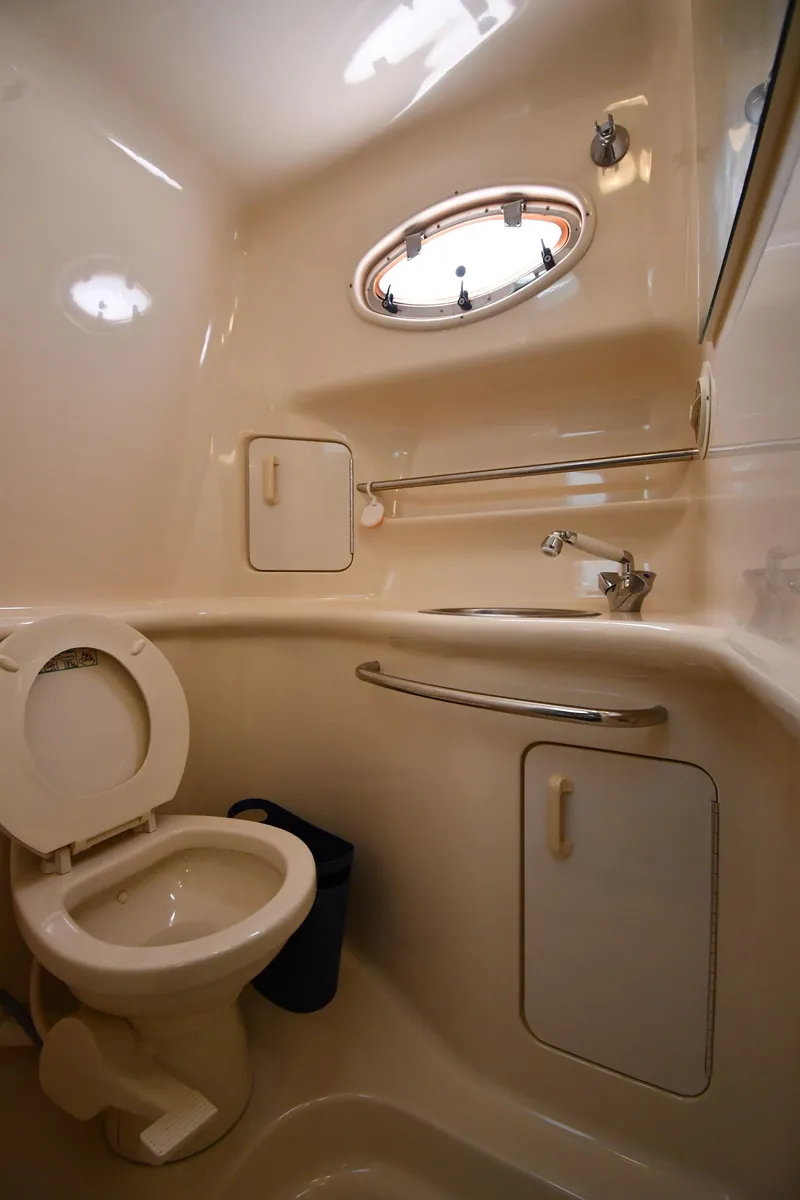 Slide: The Image of Bathroom interior of 1995 Sea Ray 330 Sundancer yacht, featuring toilet and porthole window. - 49