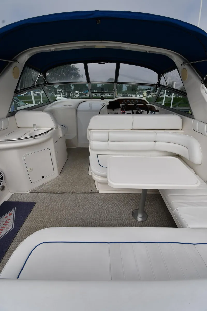 Slide: The Image of 1995 Sea Ray 330 Sundancer interior with white seating and table, under blue canopy. - 8