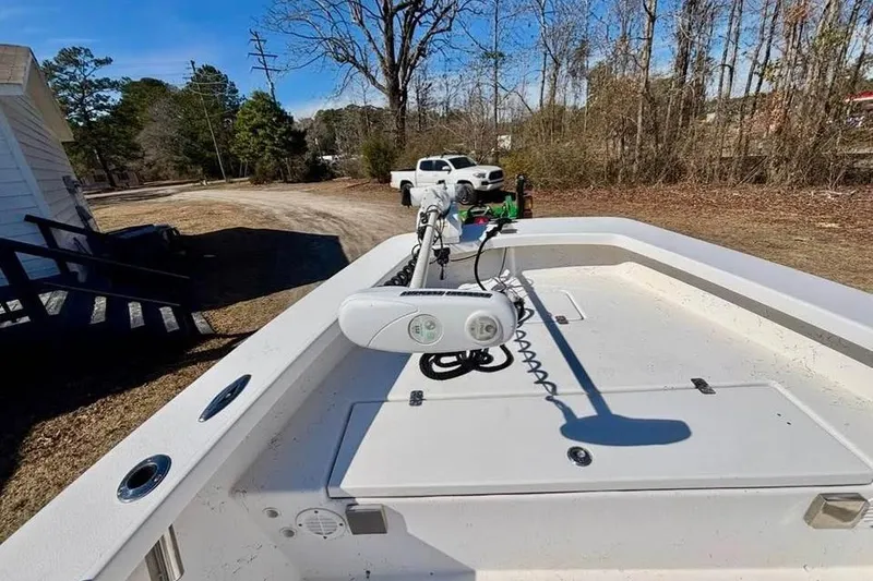 Slide: The Image of 2018 Intruder 23 boat with trolling motor, parked outdoors near trees and a white truck. - 3