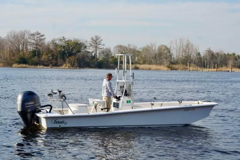 Slide: The Image of 2018 Intruder 23 boat on calm water with a person standing at the helm. - 7