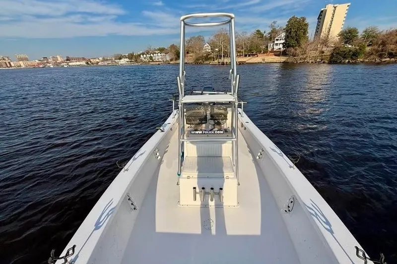 Slide: The Image of 2018 Intruder 23 boat on calm water with cityscape and trees in the background. - 9
