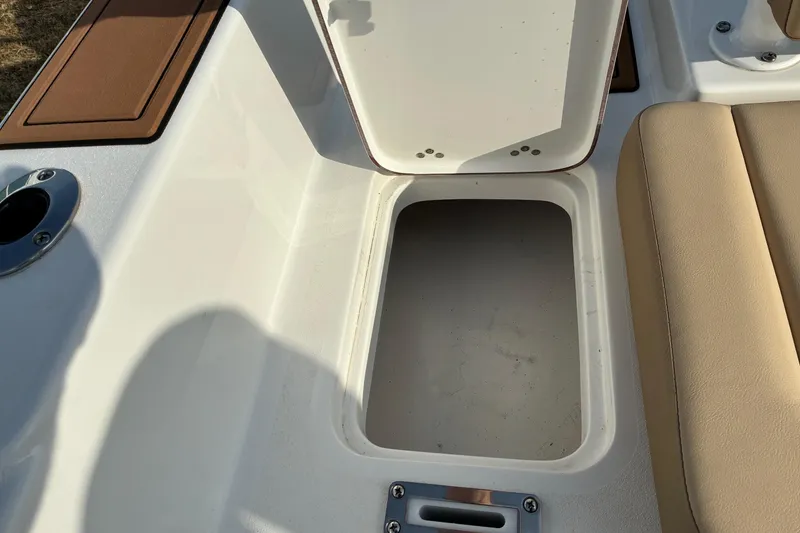 Slide: The Image of Open storage compartment on 2026 Sea Pro 245FLX Sandbar boat, featuring beige seating. - 18