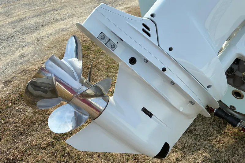 Slide: The Image of 2026 Sea Pro 245FLX Sandbar boat engine with shiny propeller on grass. - 7