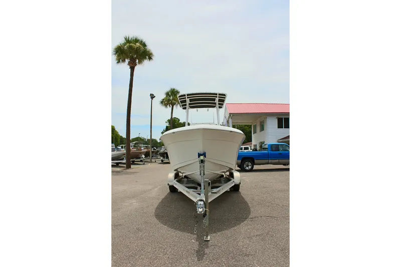 Slide: The Image of 2024 Clear Water 2200 CC boat on trailer, parked near palm trees and buildings. - 4