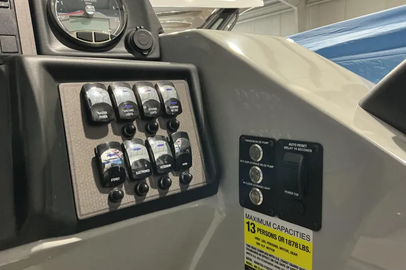 Slide: The Image of Control panel of 2026 Manitou Encore RF SHP575 230 boat with switches and capacity label. - 10