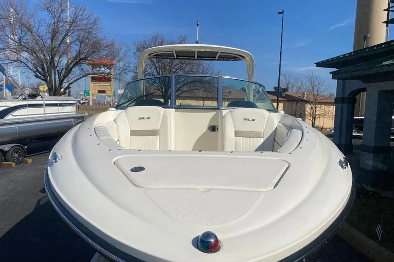 Slide: The Image of 2006 Sea Ray 270 SLX boat with white seating, docked outdoors under clear blue sky. - 15