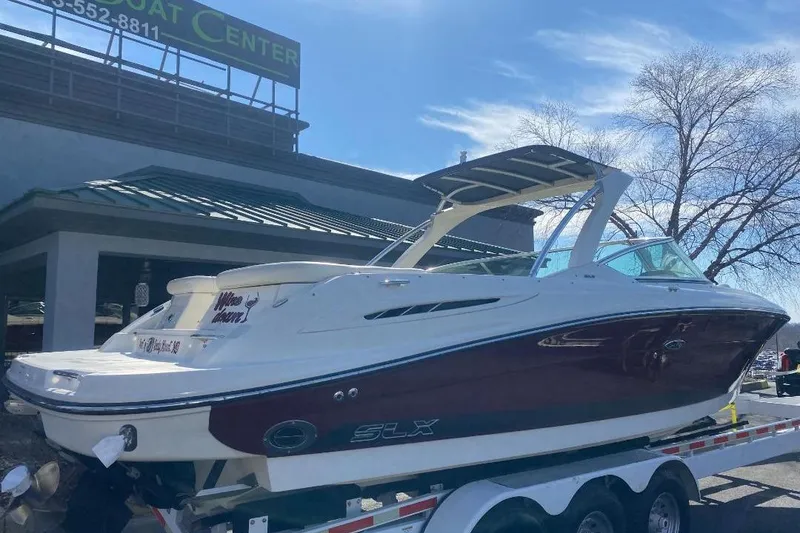 Slide: The Image of 2006 Sea Ray 270 SLX boat on trailer at dealership under clear sky. - 2
