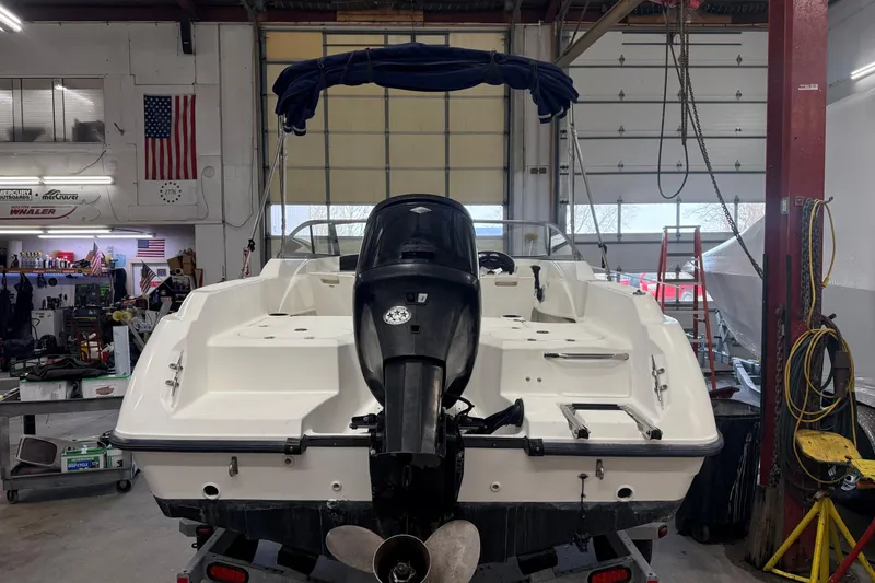 Slide: The Image of 2003 Boston Whaler 180 Ventura boat in a workshop, rear view with motor. - 2
