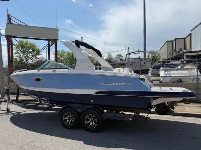 Slide: The Image of 2023 Chaparral 267 SSX boat on trailer, blue and white design, parked outdoors. - 6