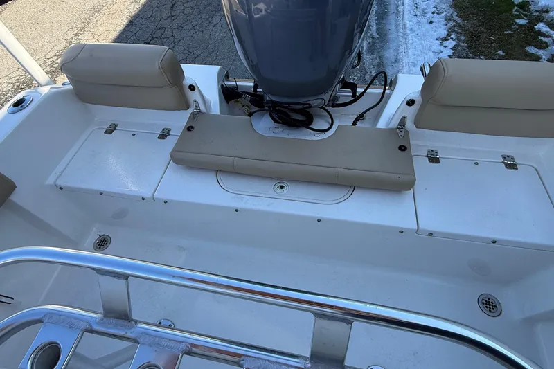 Slide: The Image of 2017 Key West 189 FS boat interior with seating and motor, parked on pavement. - 17