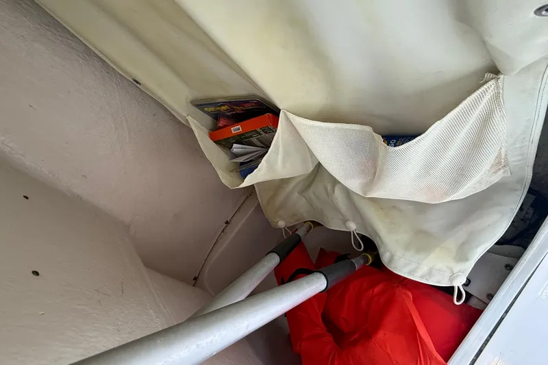 Slide: The Image of Storage compartment in a 2017 Key West 189 FS boat with safety gear and manuals. - 25
