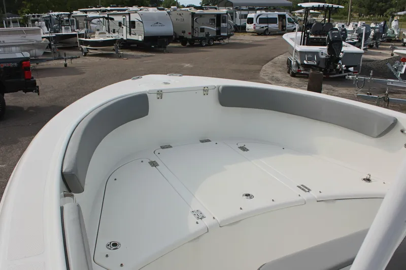 Slide: The Image of 2024 Clearwater 2200 CC boat interior with cushioned seating, parked among RVs and trailers. - 20