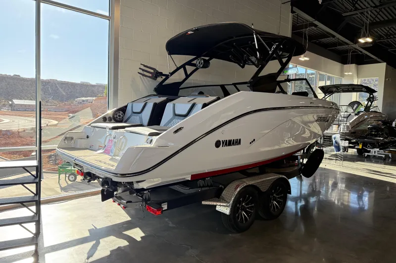 Slide: The Image of 2026 Yamaha Boats 222XD in showroom, sleek design, white exterior, on trailer. - 23