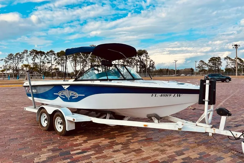 The Image of 2001 Correct Craft Air Nautique boat on trailer, parked on brick pavement under a cloudy sky. - 1