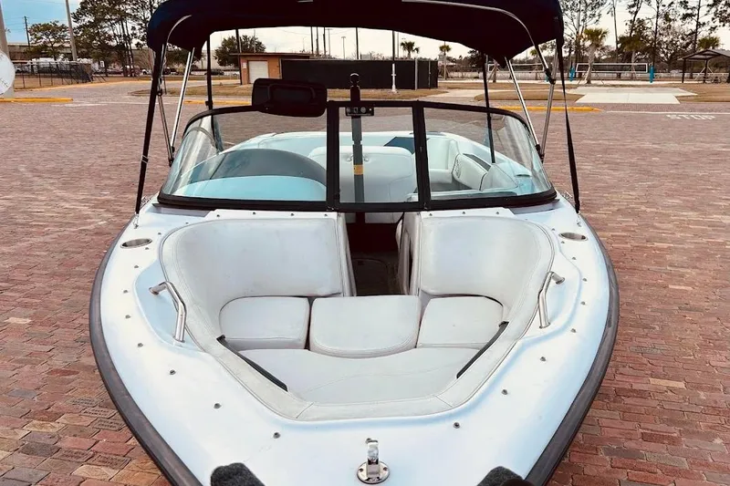 Slide: The Image of 2001 Correct Craft Air Nautique boat with white seating and canopy, parked on brick pavement. - 16
