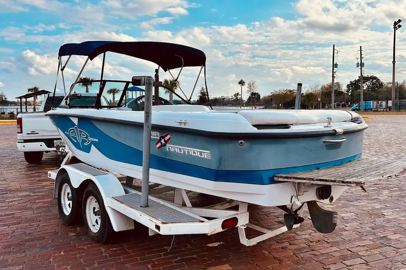 Slide: The Image of 2001 Correct Craft Air Nautique boat on trailer, parked on brick pavement under a cloudy sky. - 3