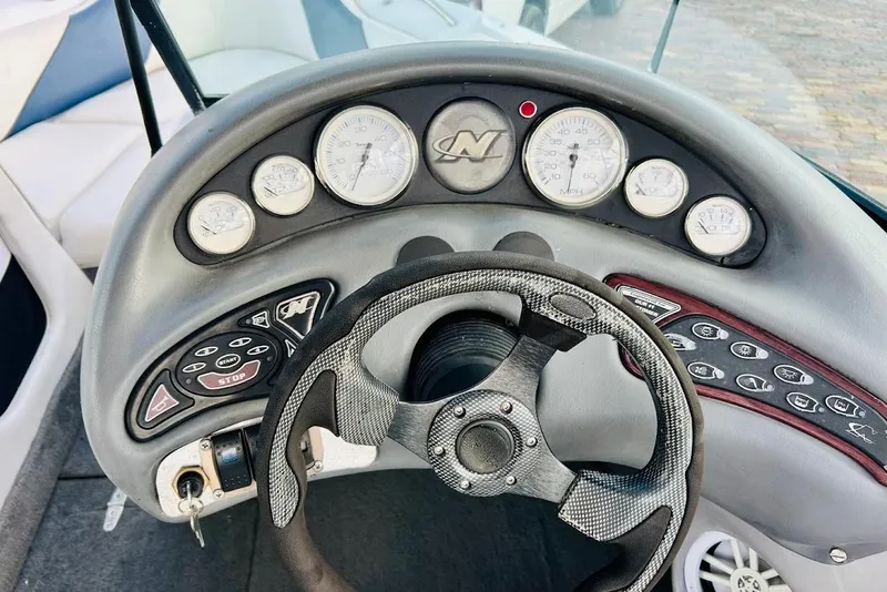 Slide: The Image of 2001 Correct Craft Air Nautique boat interior with seating and steering wheel, docked near water. - 10