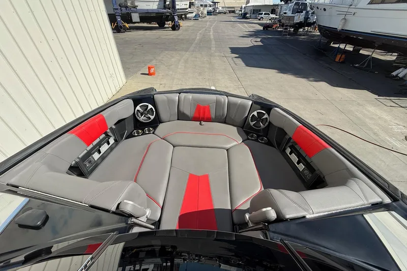Slide: The Image of 2021 Malibu Wakesetter 23 MXZ boat interior with gray and red seating, docked outdoors. - 14