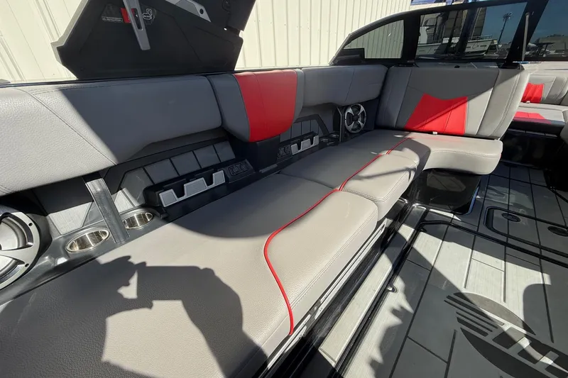 Slide: The Image of 2021 Malibu Wakesetter 23 MXZ interior with gray and red seating, cup holders, and speakers. - 23