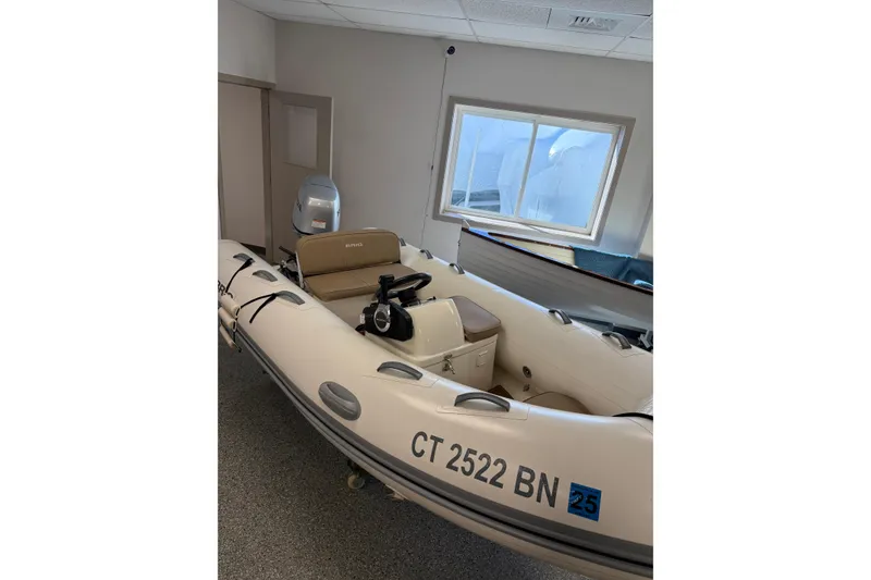 Slide: The Image of 2021 Brig Falcon 360 inflatable boat in indoor storage, featuring a sleek design and outboard motor. - 1