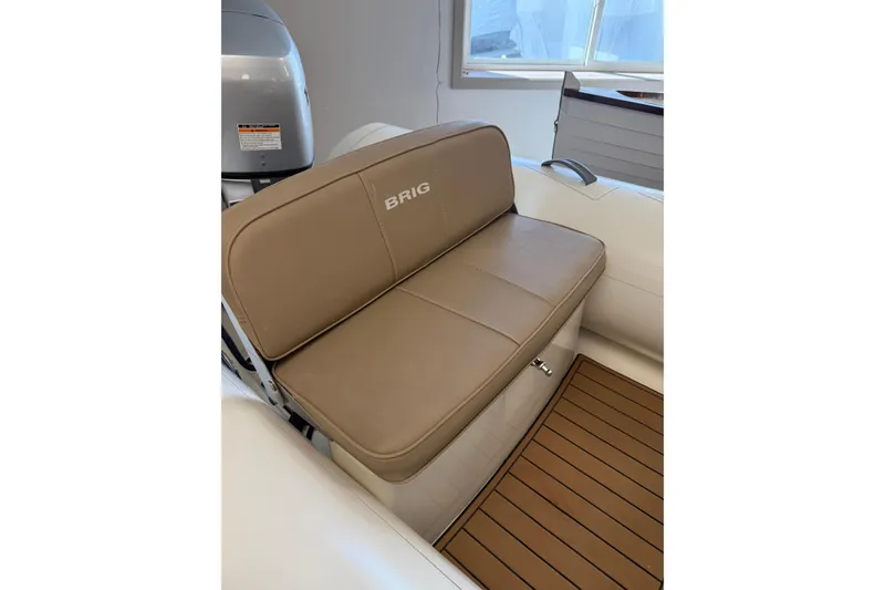 Slide: The Image of 2021 Brig Falcon 360 boat interior with tan seating and wooden flooring. - 7